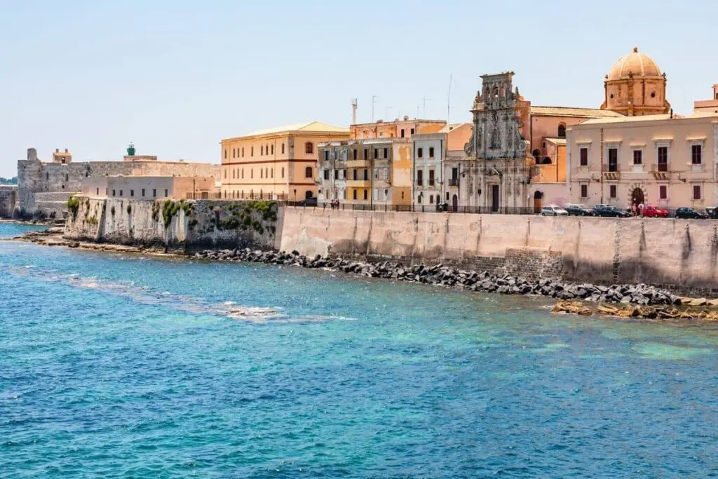 Sea in the foreground of the photot with brick buildings in the background in Syracuse