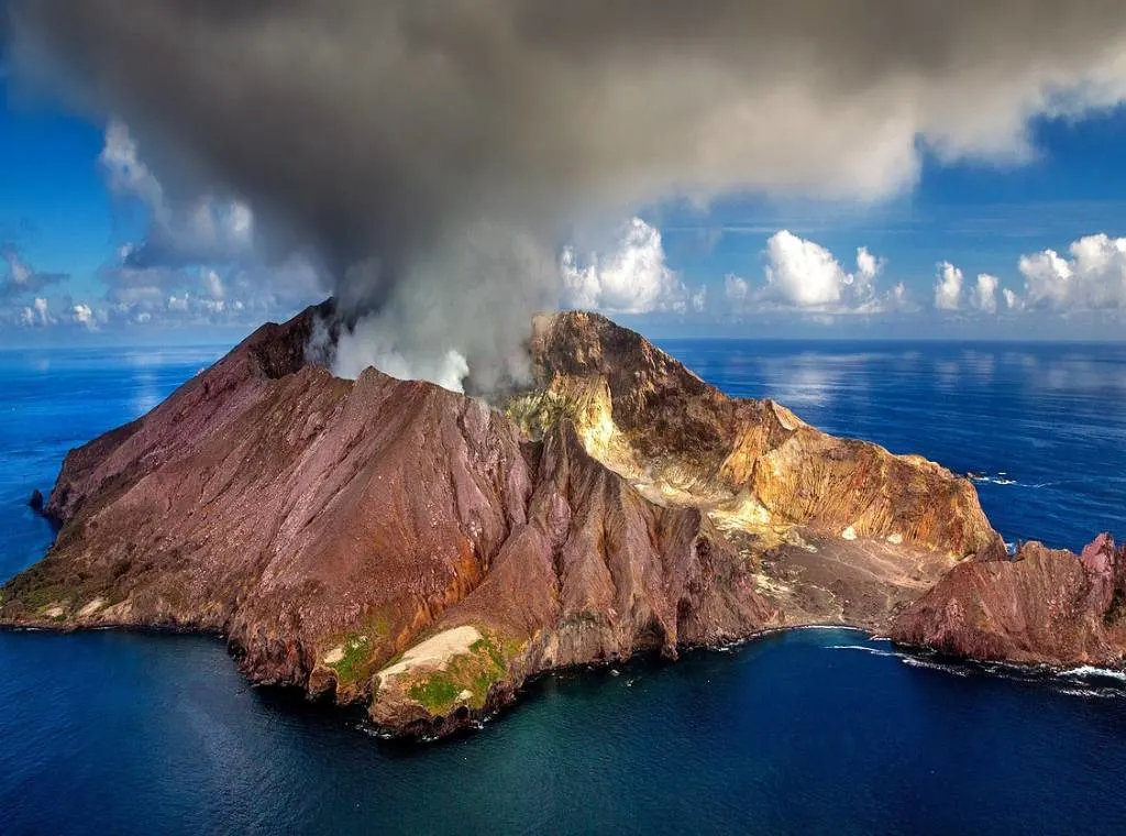 a volcano with smoke emanating from the cone in the By of Islands