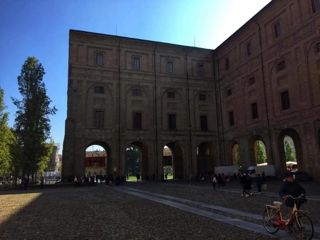 A museum in Parma that is made of grey bricks and erected at a 90 degree angle with arches at the lowest level