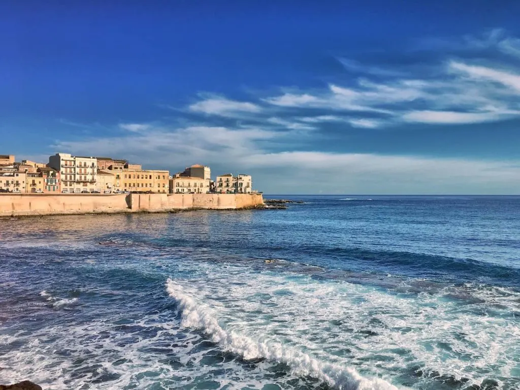 Ortigia in Syracuse in the background of the shot witht he sea in the foreground.