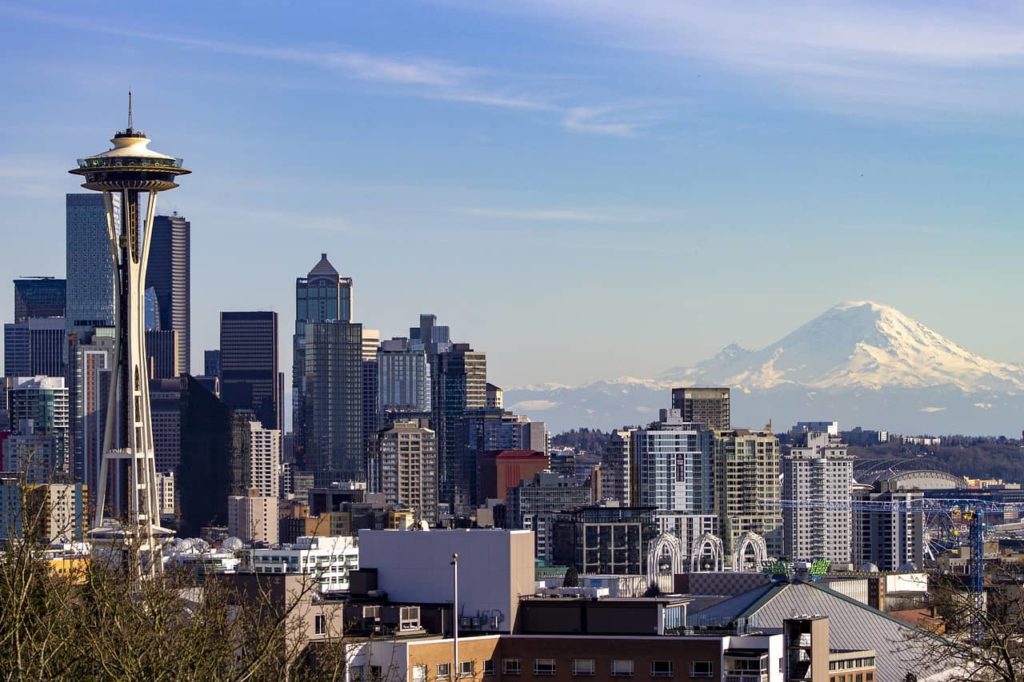 seattle skyline by day with space needl to the left and mountain to the right