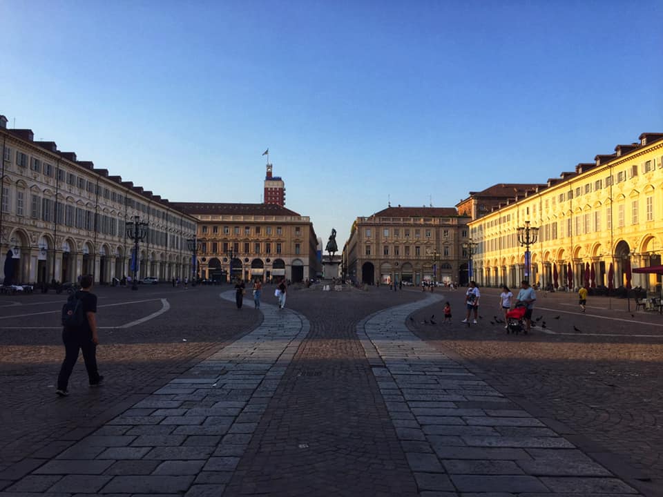 square in turin with a statue at the end in between buildings