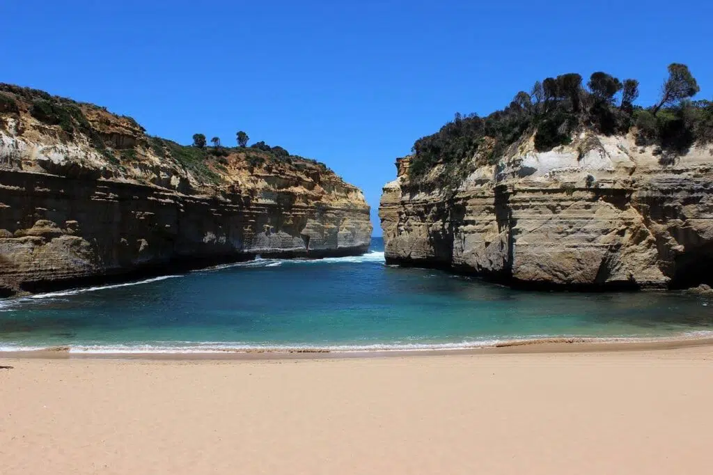 loch ard gorge om the great ocean road, two cliffs protruding out into sea with a cove and beach in the foreground