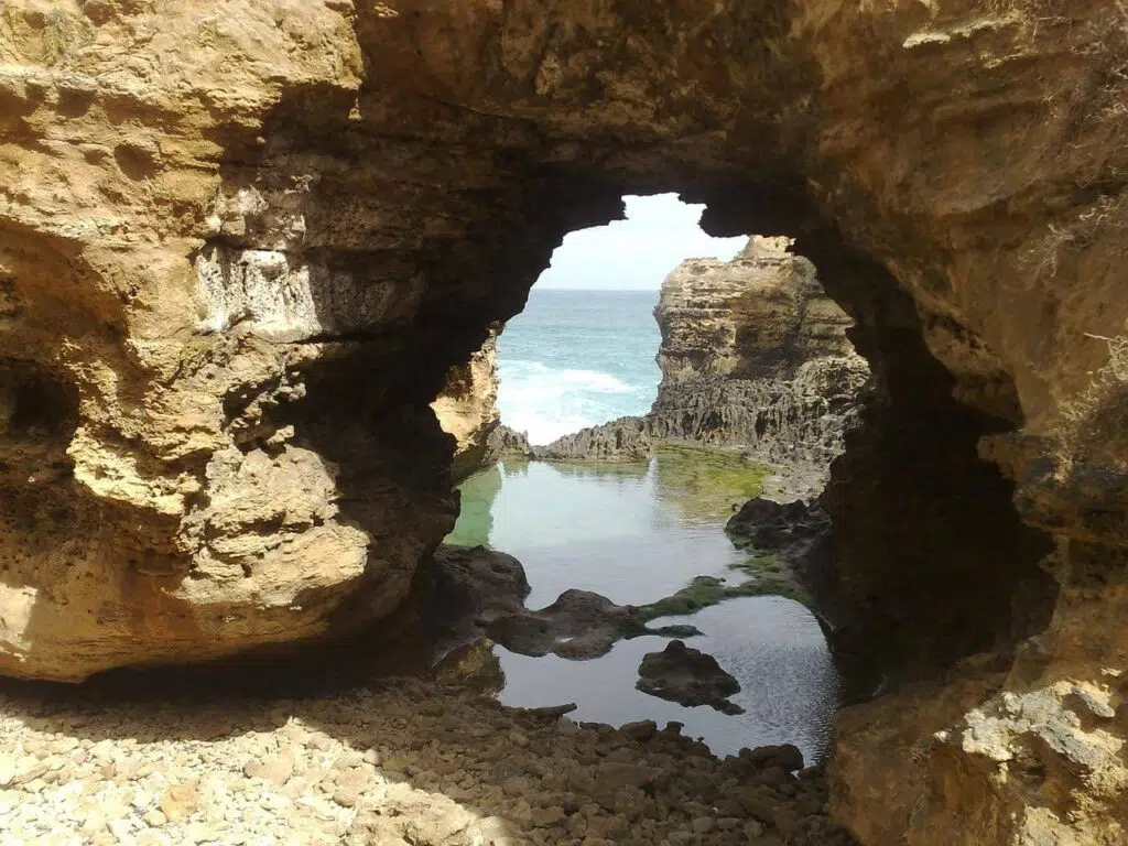 the grotto on the great ocean road, a small arch with water on one side and sand in the foreground