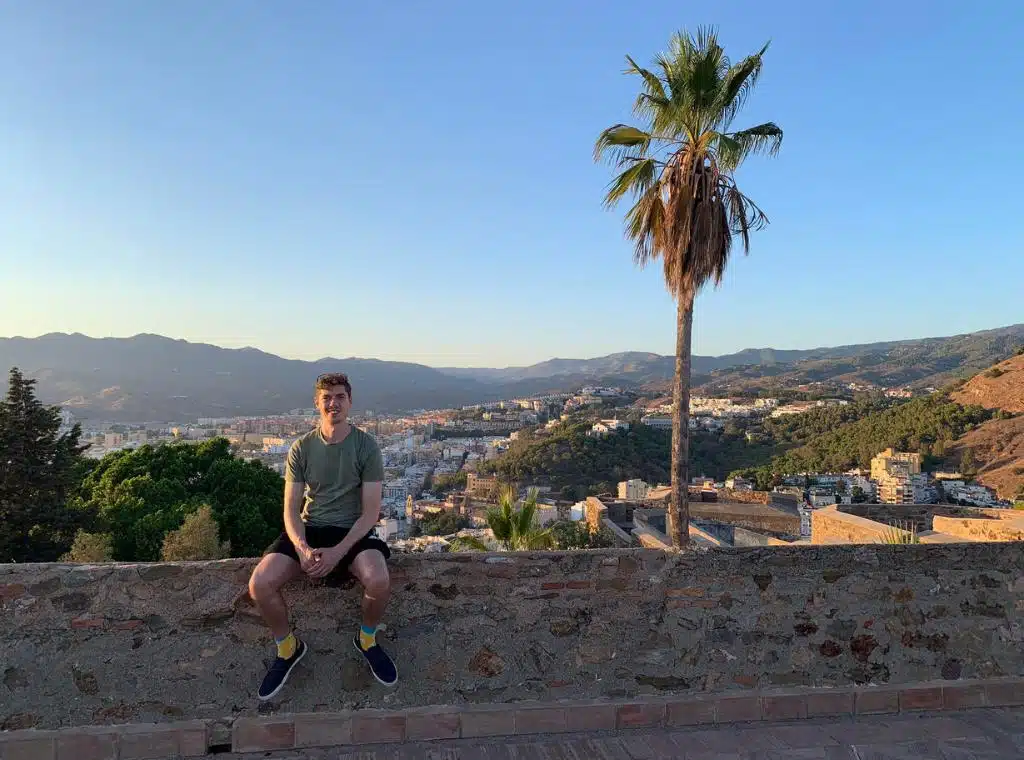 me in malaga sitting on the ledge of a castle overlooking some hills