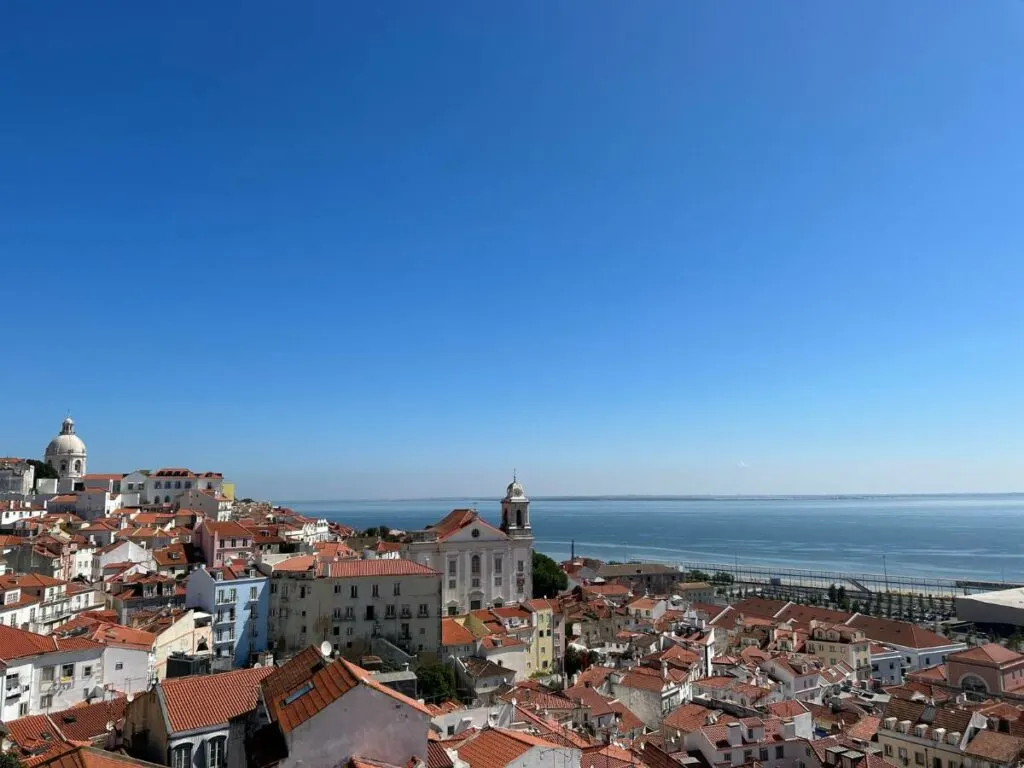 blue skies in Lisbon with terracotta roofs and the ocean visible
