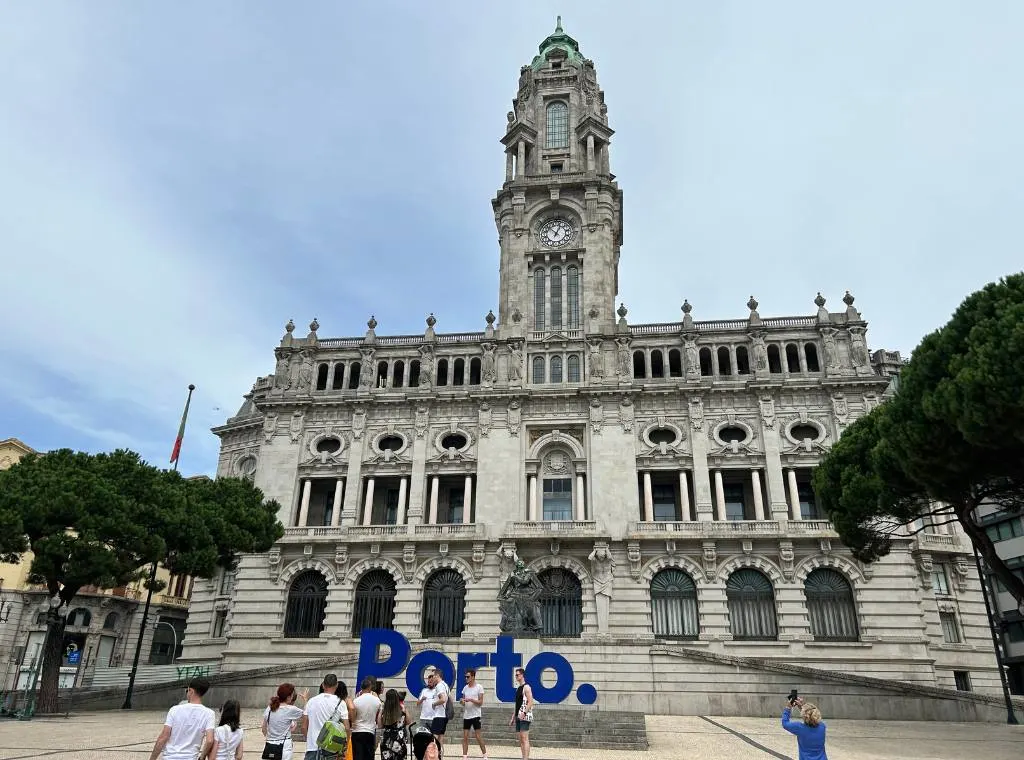 porto city hall with a blue sign spelling out Port on front of it with people queuing to take a photo