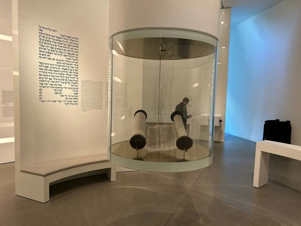 an old torah enclosed in a glass cylinder at the Jewish Museum in Berlin
