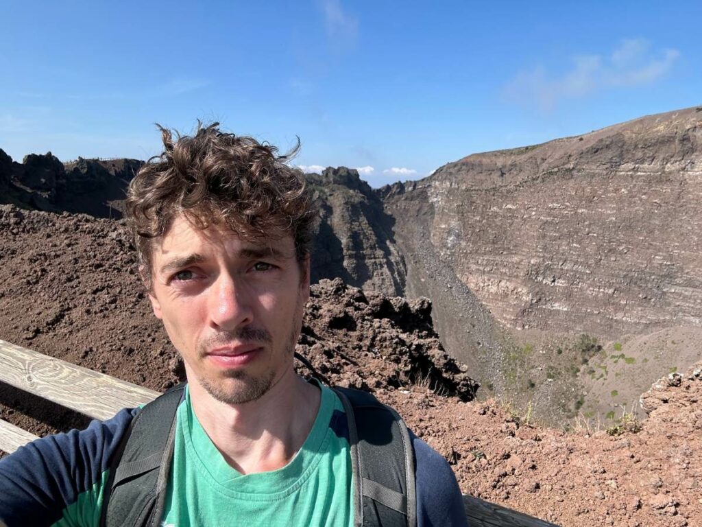 Tom atop Mount Vesuvius with the inside of the cone visible in the background