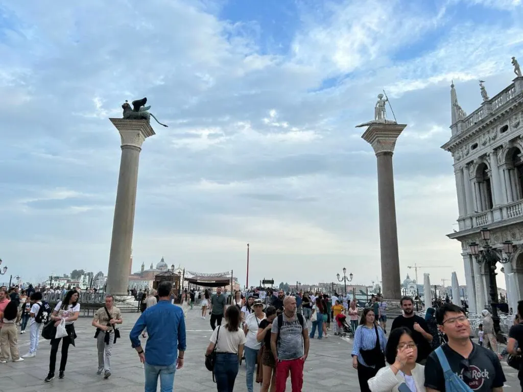 two columns in Piazza San Marco with people walking around the square 