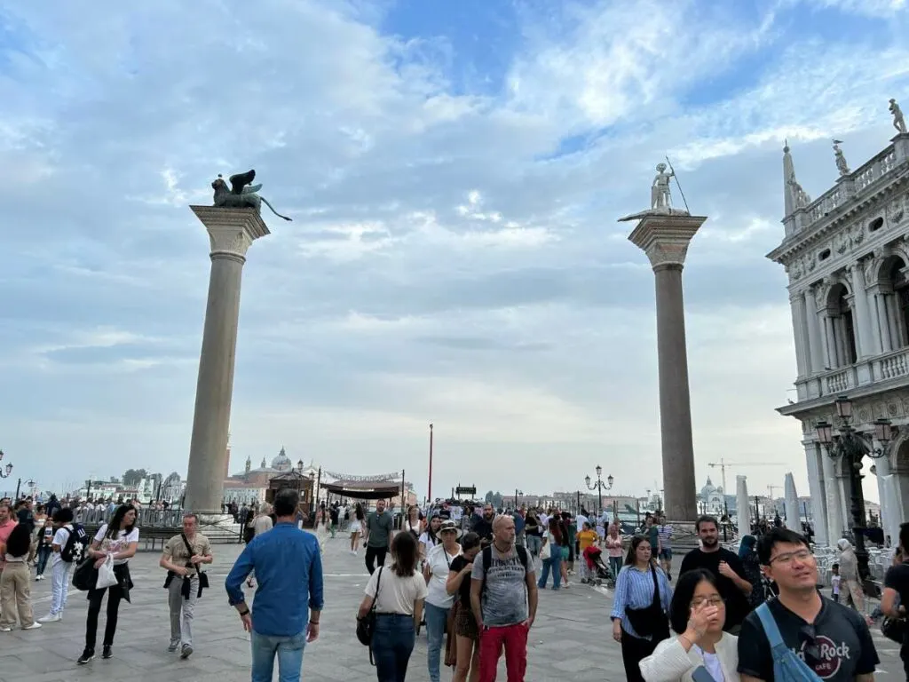 two columns in Piazza San Marco with people walking around the square
