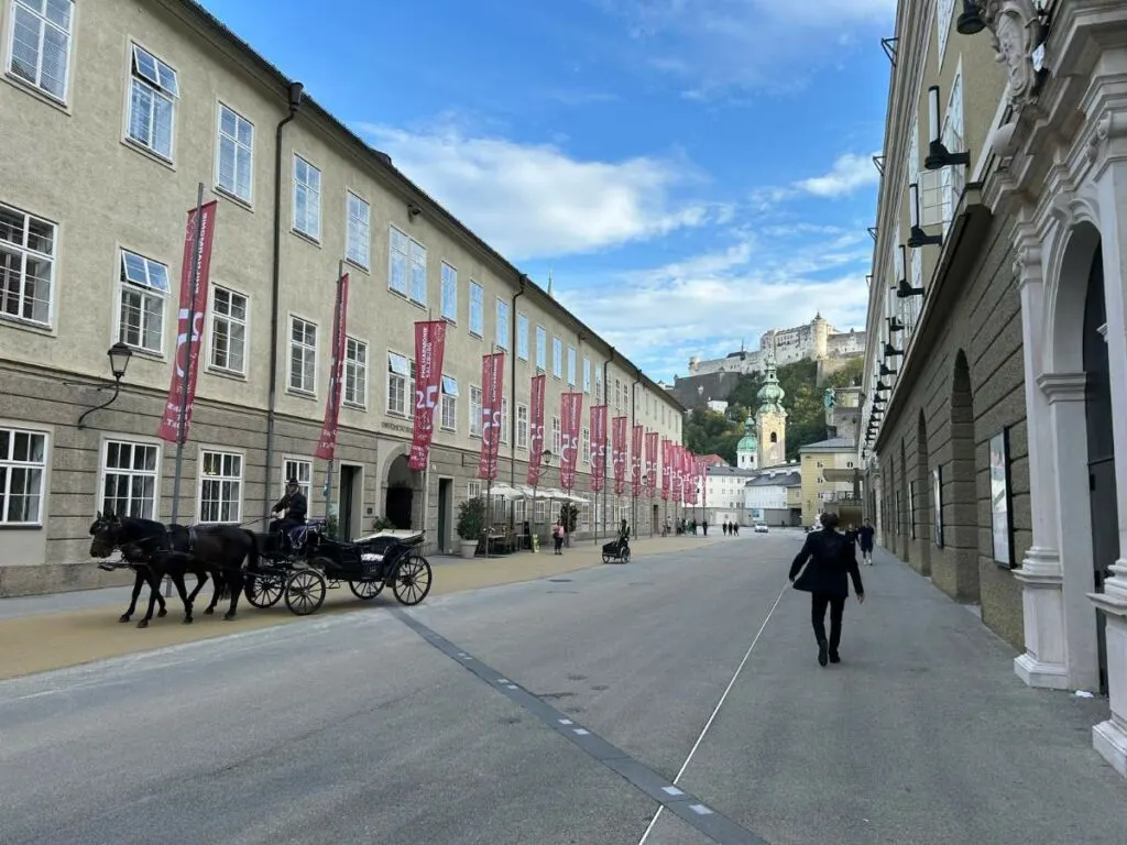 a horse and carriage going past the philharmonie building in salzburg