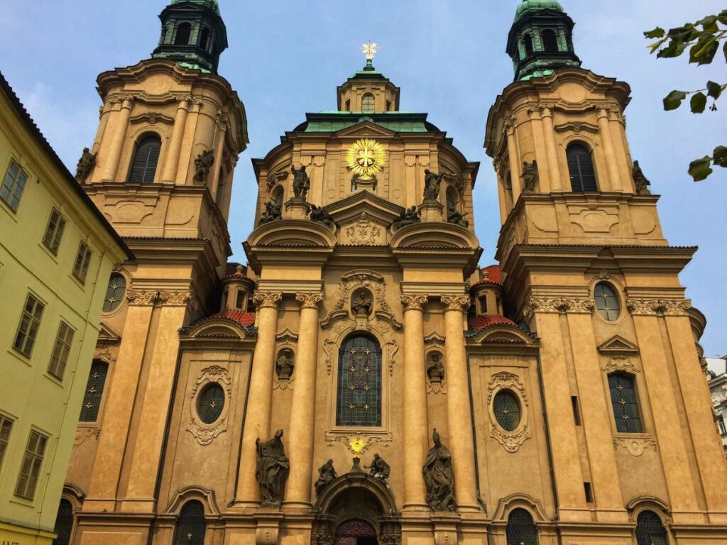 a yellow-colored church in Prague with two spires